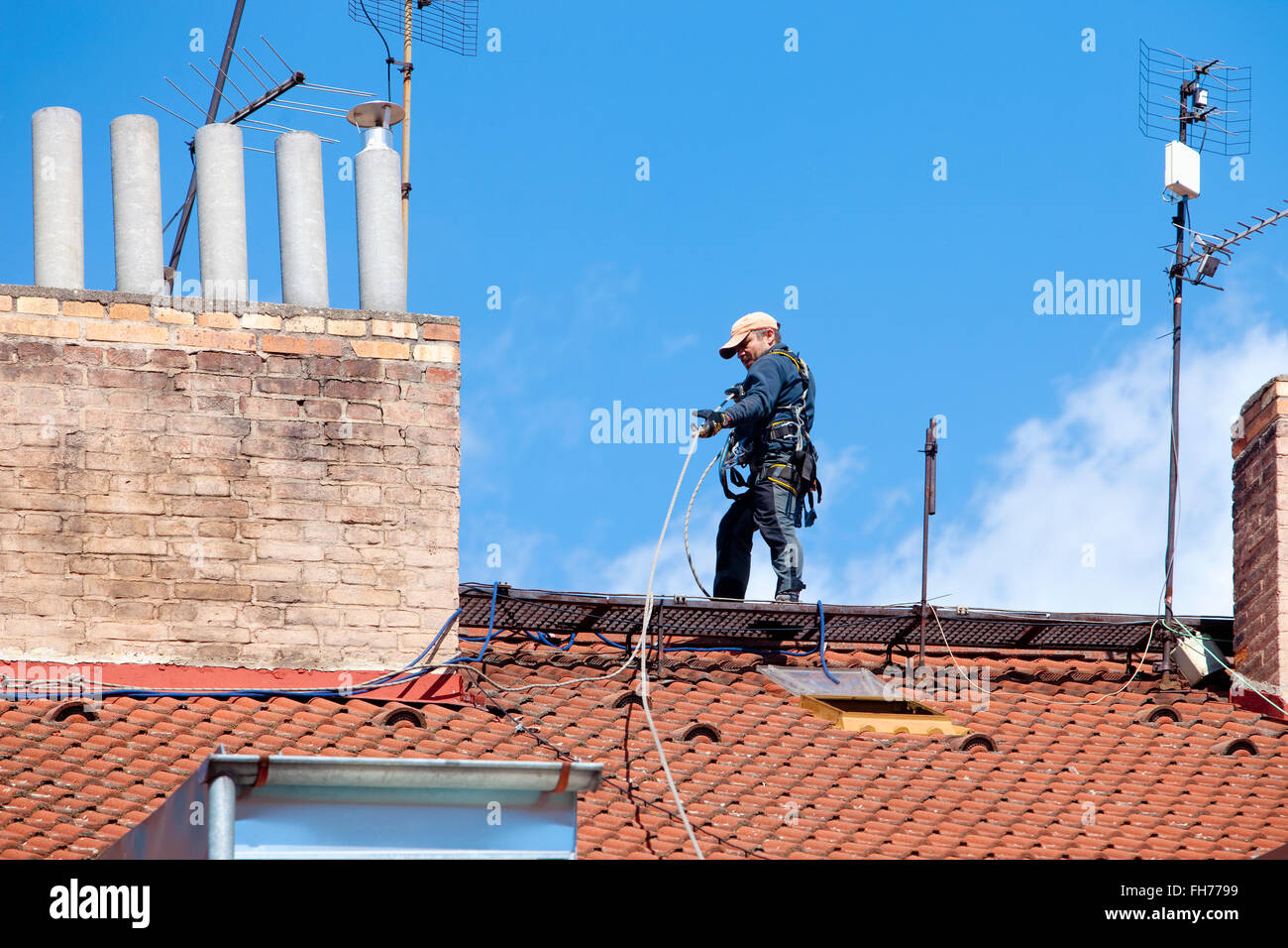 Instandhalter mit Sicherheitsgurt auf einem Hausdach Stockfoto