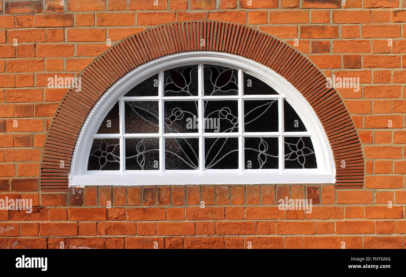 Außen ein Backsteingebäude mit einem gewölbten Fenster. Stockfoto