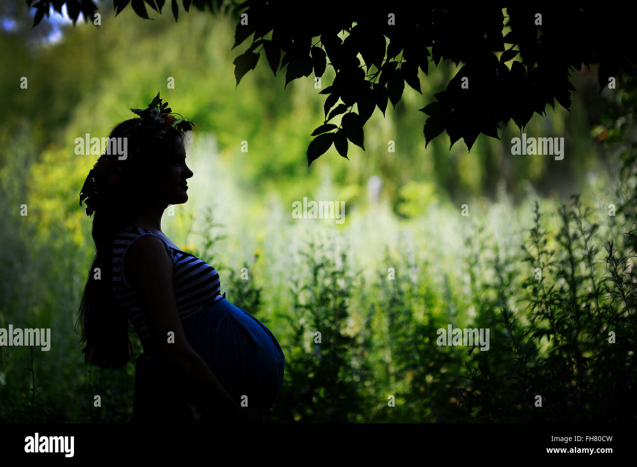 Silhouette einer glücklich schwanger Frau im Garten Stockfoto