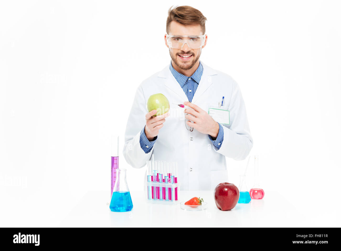 Männliche Chemiker tun Injektion von GVO in Apfel isoliert auf weißem Hintergrund Stockfoto