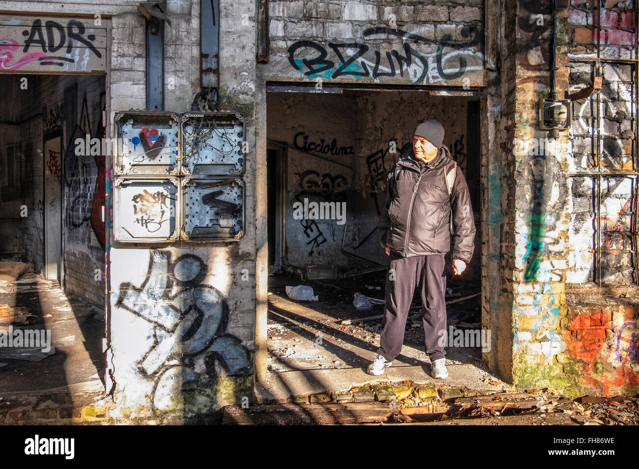 Älterer Mann erforscht alten verlassenen und Graffiti bedeckt Gebäude am Güterbahnhof Zug Bahnhof Pankow, Berlin. Stockfoto
