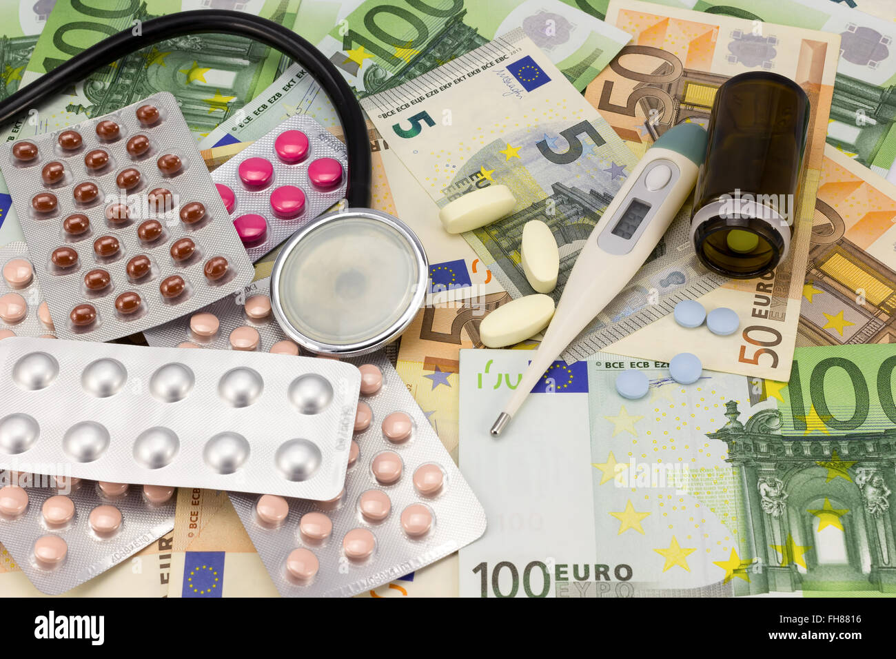medizinische Pillen, Stethoskop und Thermometer in Euro Geld Hintergrund als Symbol der Kosten im Gesundheitswesen Stockfoto