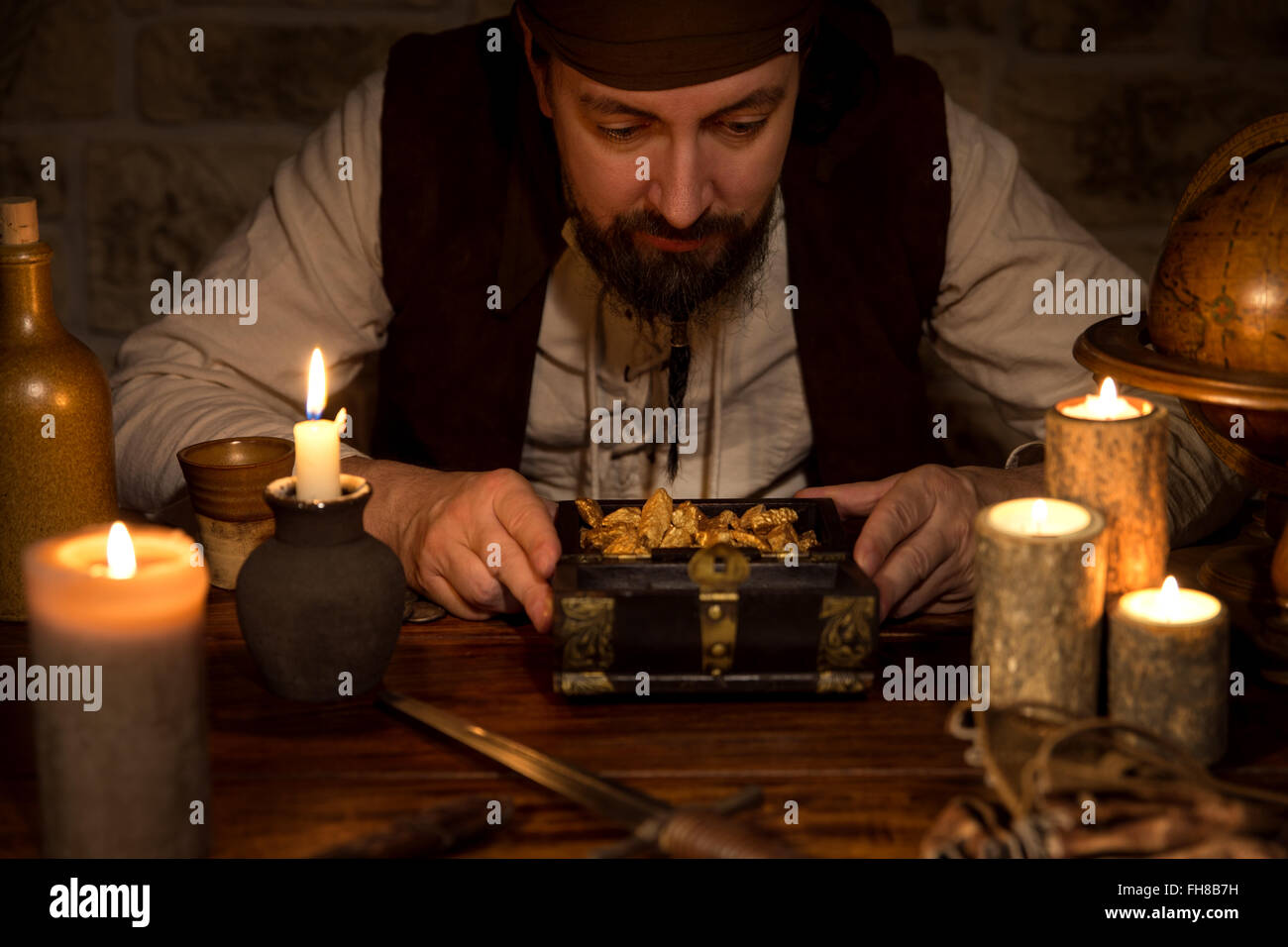 ein Pirat mit einem Schatz von Gold, viele Kerzen und alte accessoires Stockfoto