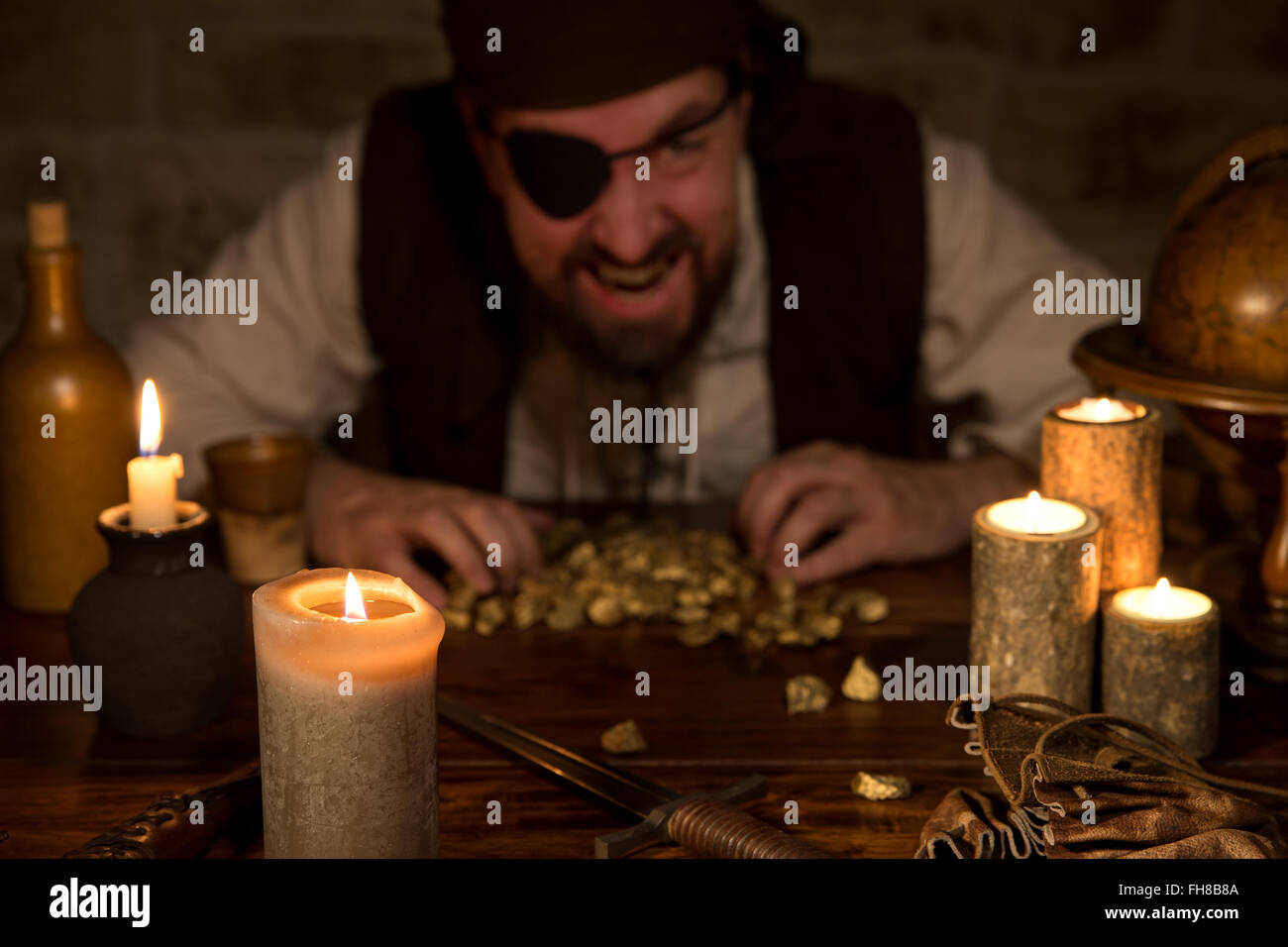 eine gierige Piraten mit einem Goldschatz hinter vielen Kerzen Stockfoto