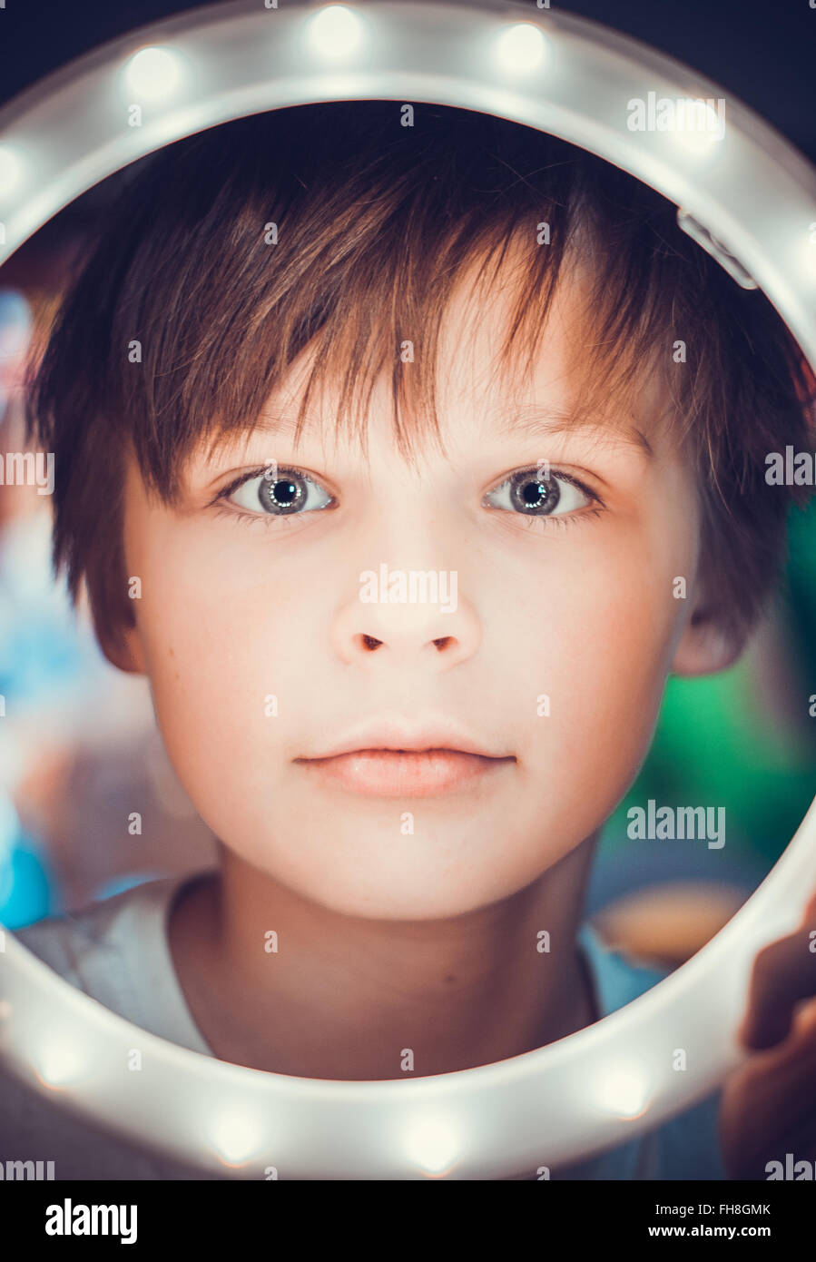 Überrascht Junge schaut in die Kamera durch einen leuchtenden Kreis als astronaut Stockfoto