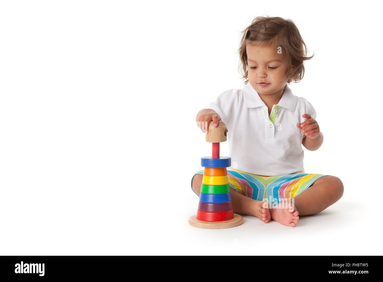 Kleinkind Mädchen spielen mit farbigen Steinen auf weißem Hintergrund Stockfoto