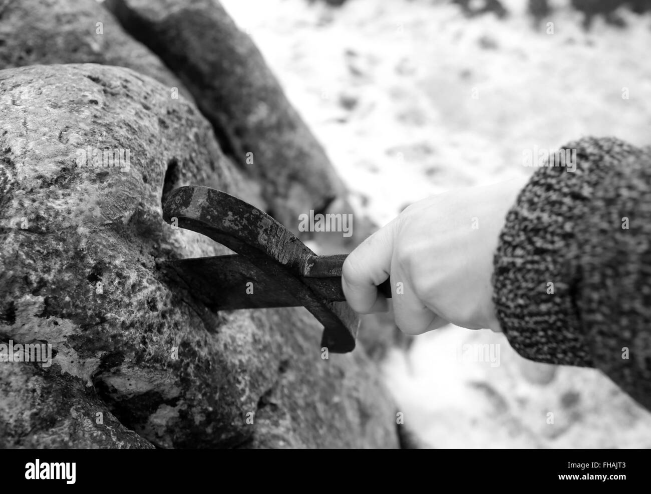 Hand des tapferen Ritters versucht, das magische Schwert Excalibur in den Stein zu entfernen Stockfoto