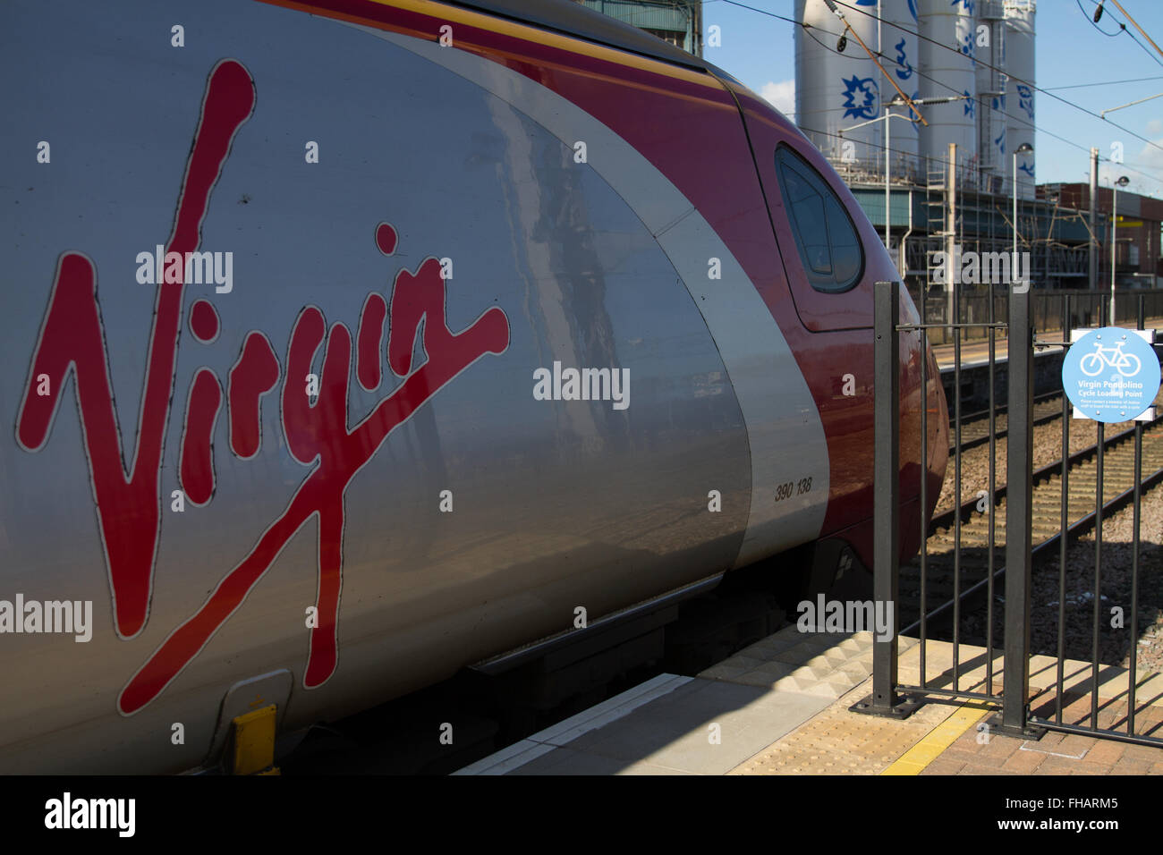 Jungfrau Pendolino-Zug an der Ladestelle am Warrington Bank Quay in hellem Sonnenlicht, Unilever Fabrik hinter Zyklus. Stockfoto