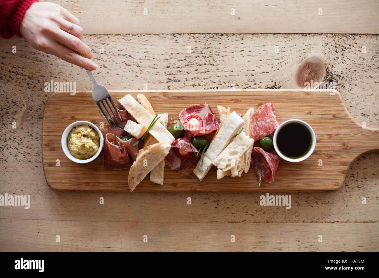 Eine Frau Hand mit einer Gabel nimmt Essen von einem Teller mit antipasti Stockfoto