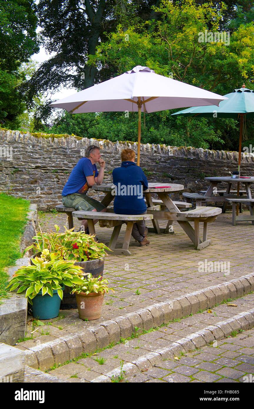 Northumberland. Mittleren gealterten paar sitzt am Picknicktisch unter Sonnenschirm. Der weiße Mönch Teestube, Blanchland. Stockfoto
