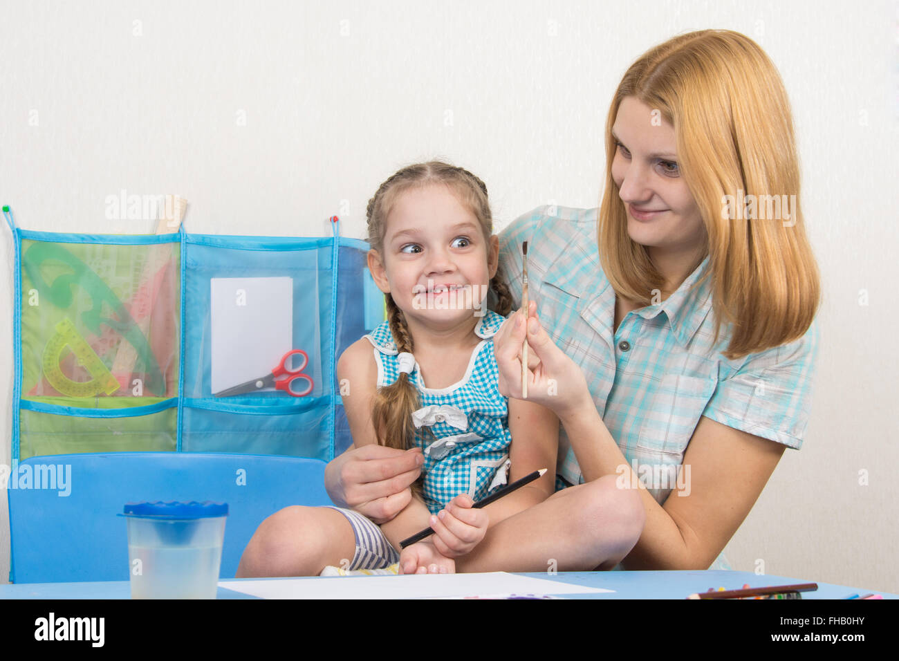 Eine fünfjähriges Mädchen beschäftigt sich mit Zeichnung mit Erwachsenen jungen schönen Mädchen sitzen am Tisch zu Hause Kinder Stockfoto