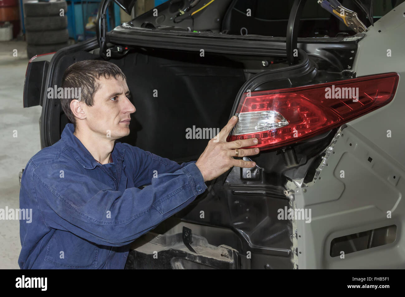 Junge Mechaniker installiert Rücklicht am Fahrzeug. Stockfoto