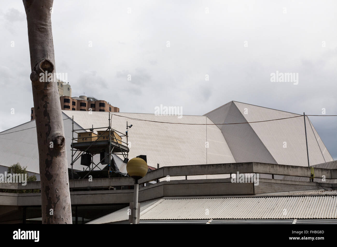 Adelaide Festival Centre Dach und Geländer mit vorübergehenden Projektion Ausrüstung Turm und Baumstamm in den Vordergrund, bewölktem Himmel Stockfoto