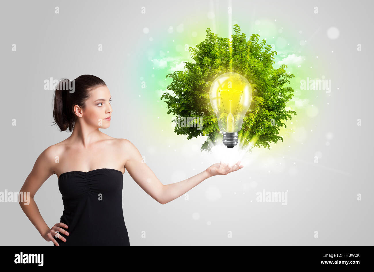 Junges Mädchen präsentieren Idee Glühbirne mit grüner Baum Stockfoto