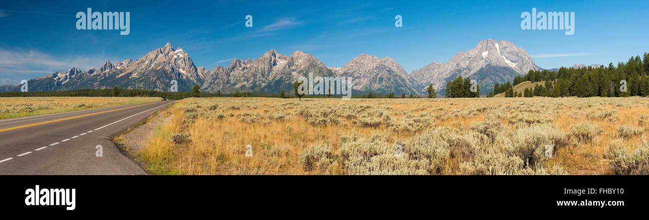 Panoramasicht auf Berge auf einsamen Straße unter blauem Himmel mit gelben braune Felder auf der Straße. Stockfoto