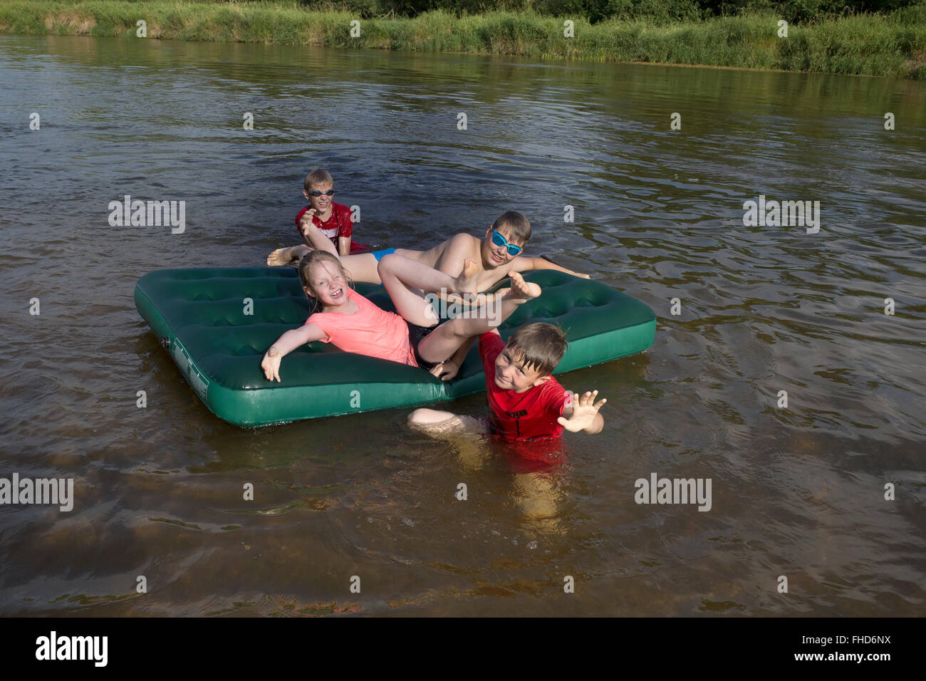Kinder im Alter von 12 bis 8, die spielen auf einer Luftmatratze am Fluss Pilica. Rzeczyca Zentralpolen Stockfoto