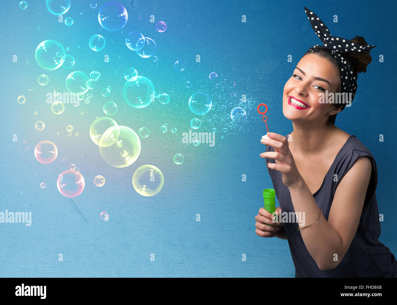 Hübsche Dame bunte Seifenblasen auf blauem Hintergrund Stockfoto