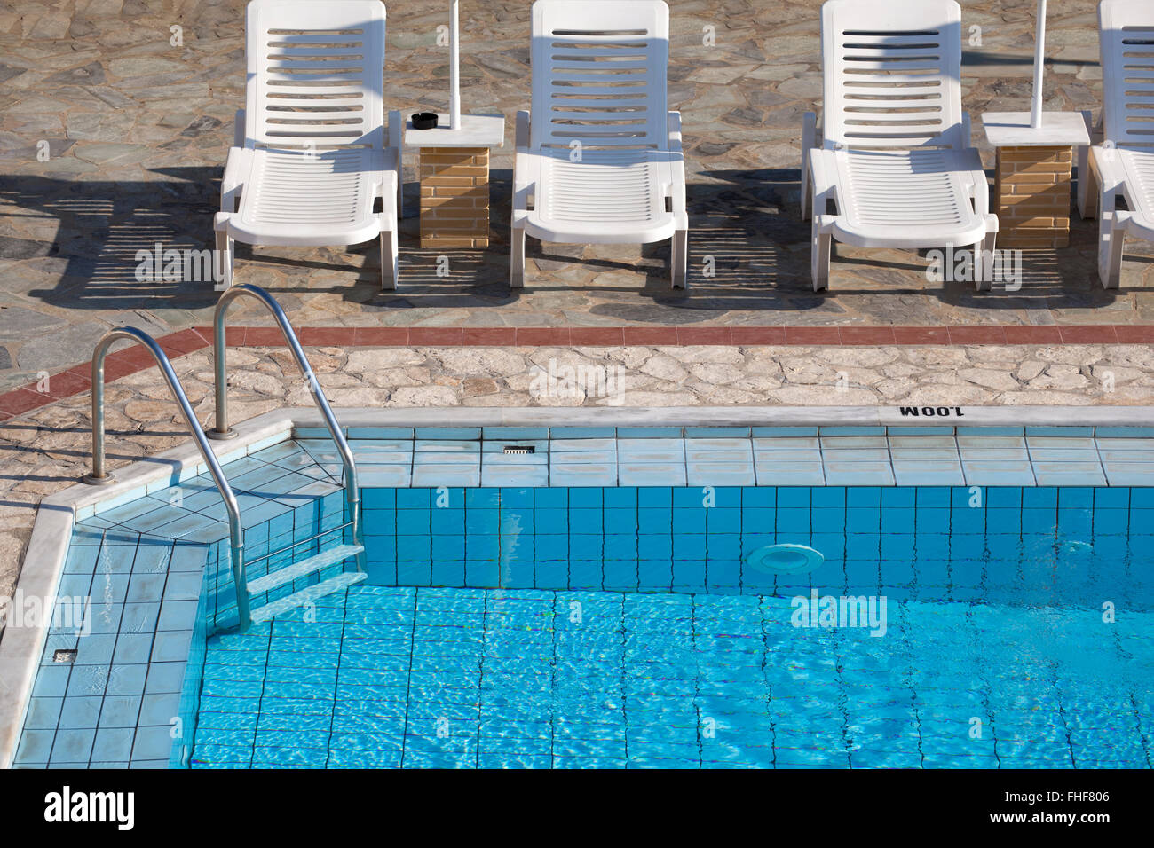 Klaren blauen Pool mit klarem Wasser und Sonnenliegen um ihn herum in einem heißen Sommermorgen. Stockfoto