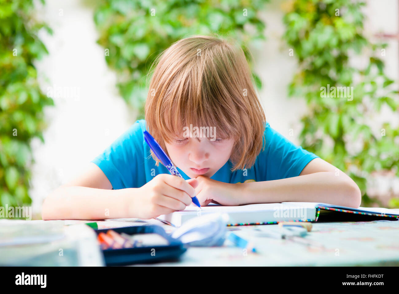 Junge mit blonden Haaren machen Hausaufgaben im freien Stockfoto