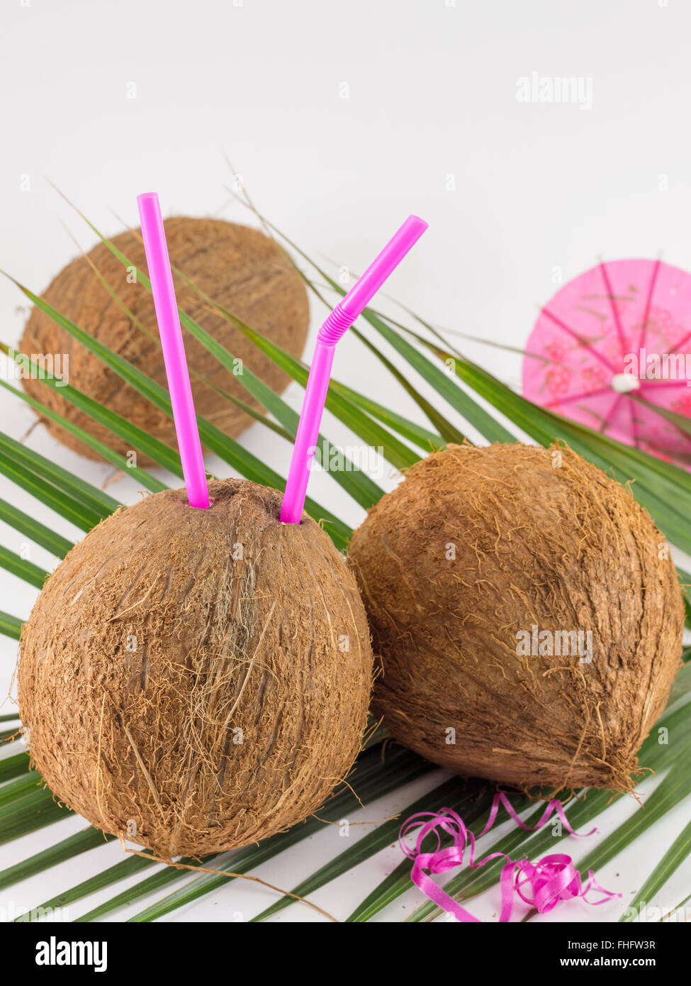Frische Kokosnuss Cocktails mit cocktail Regenschirm auf Kokosnussblättern platziert Stockfoto
