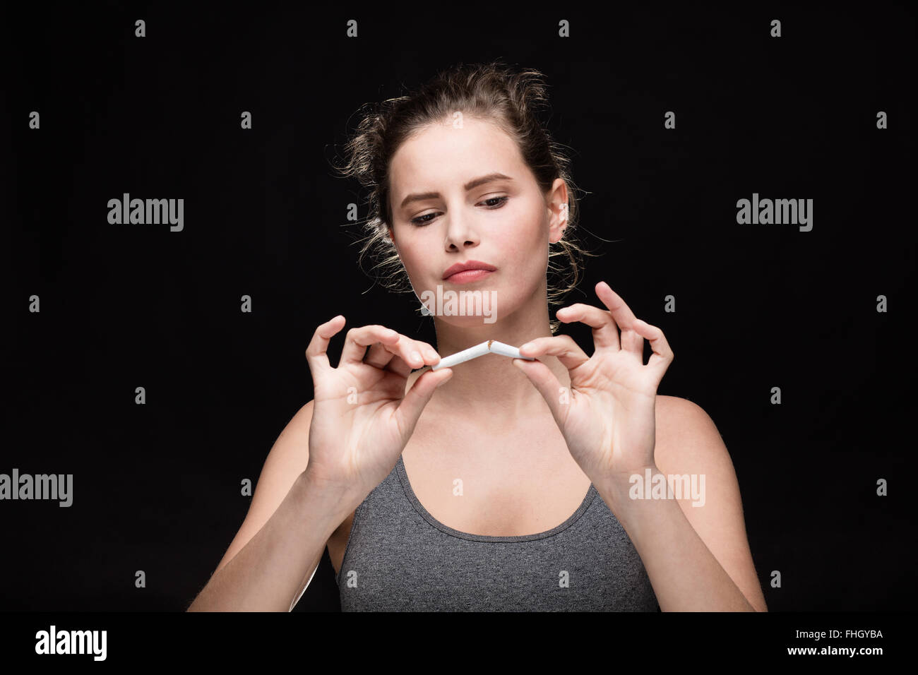 junge Frau bricht eine Zigarette, Rauchen Konzept auf schwarzem Hintergrund Stockfoto