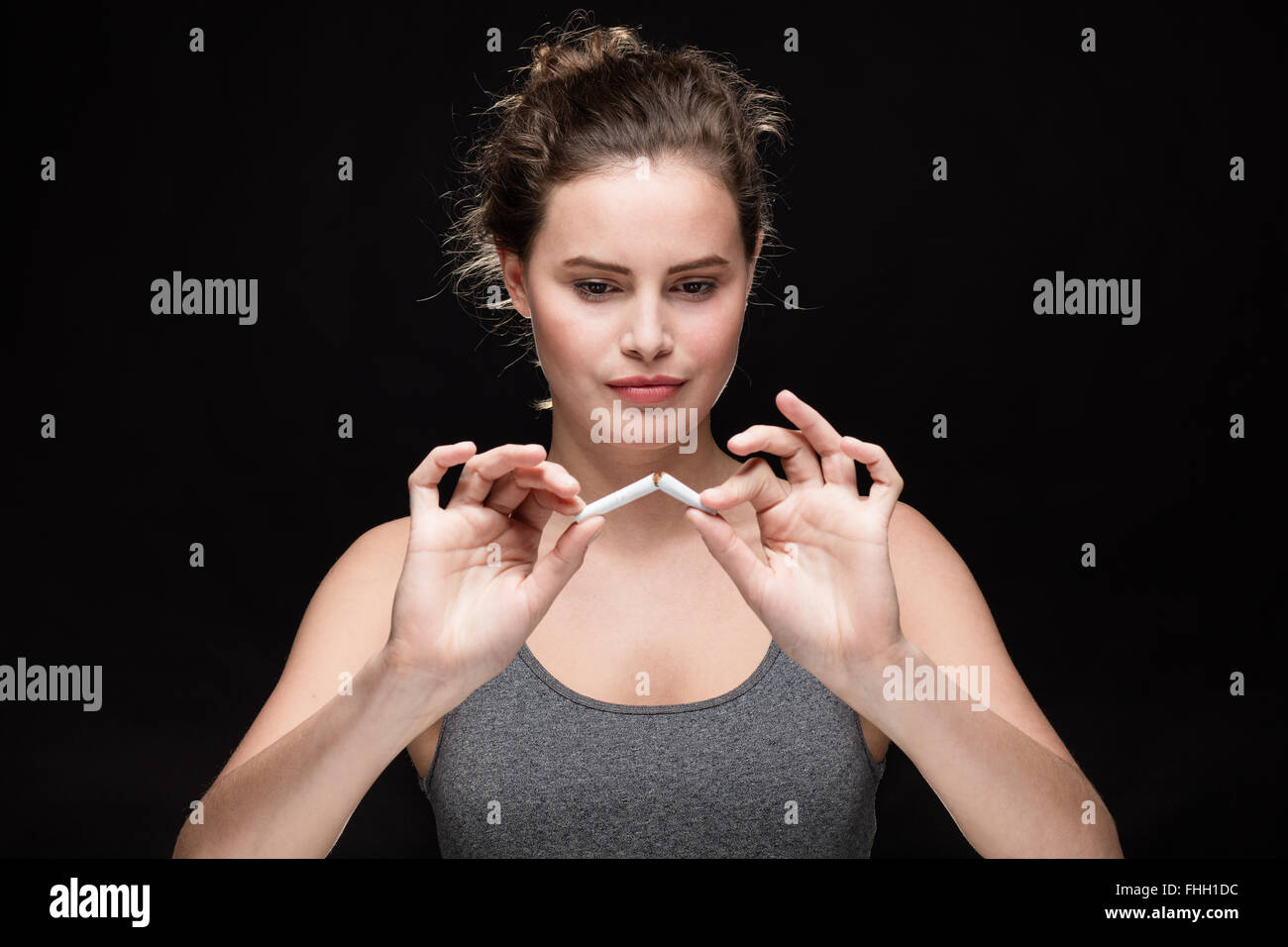 junge Frau bricht eine Zigarette, Rauchen Konzept auf schwarzem Hintergrund Stockfoto