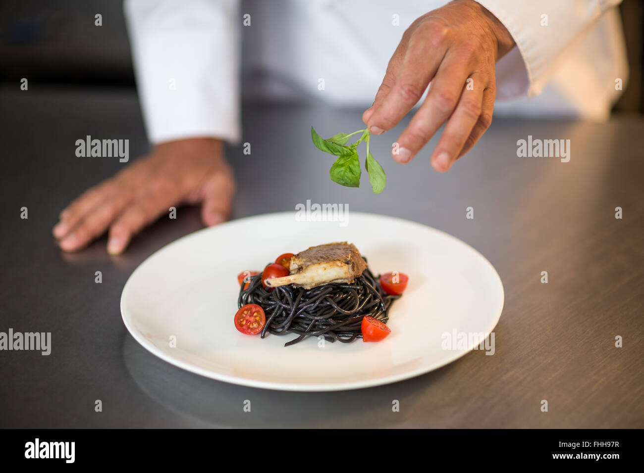 Koch, Basilikum auf Spaghetti-Gericht Stockfoto