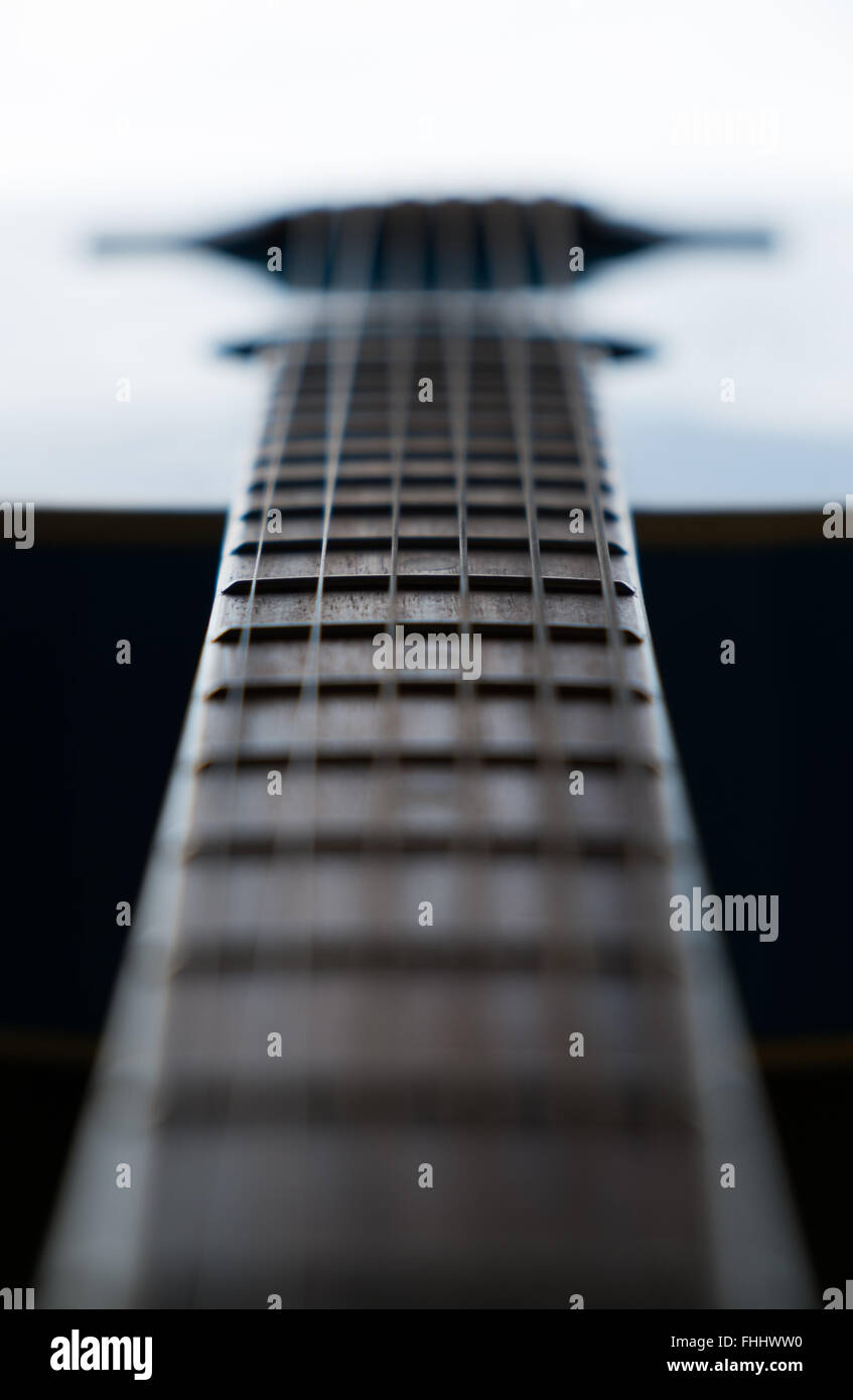 Detail der hölzernen Akustikgitarre Bünde auf einem blauen Gitarre beleuchtet und schoss mit selektiven Fokus Stockfoto