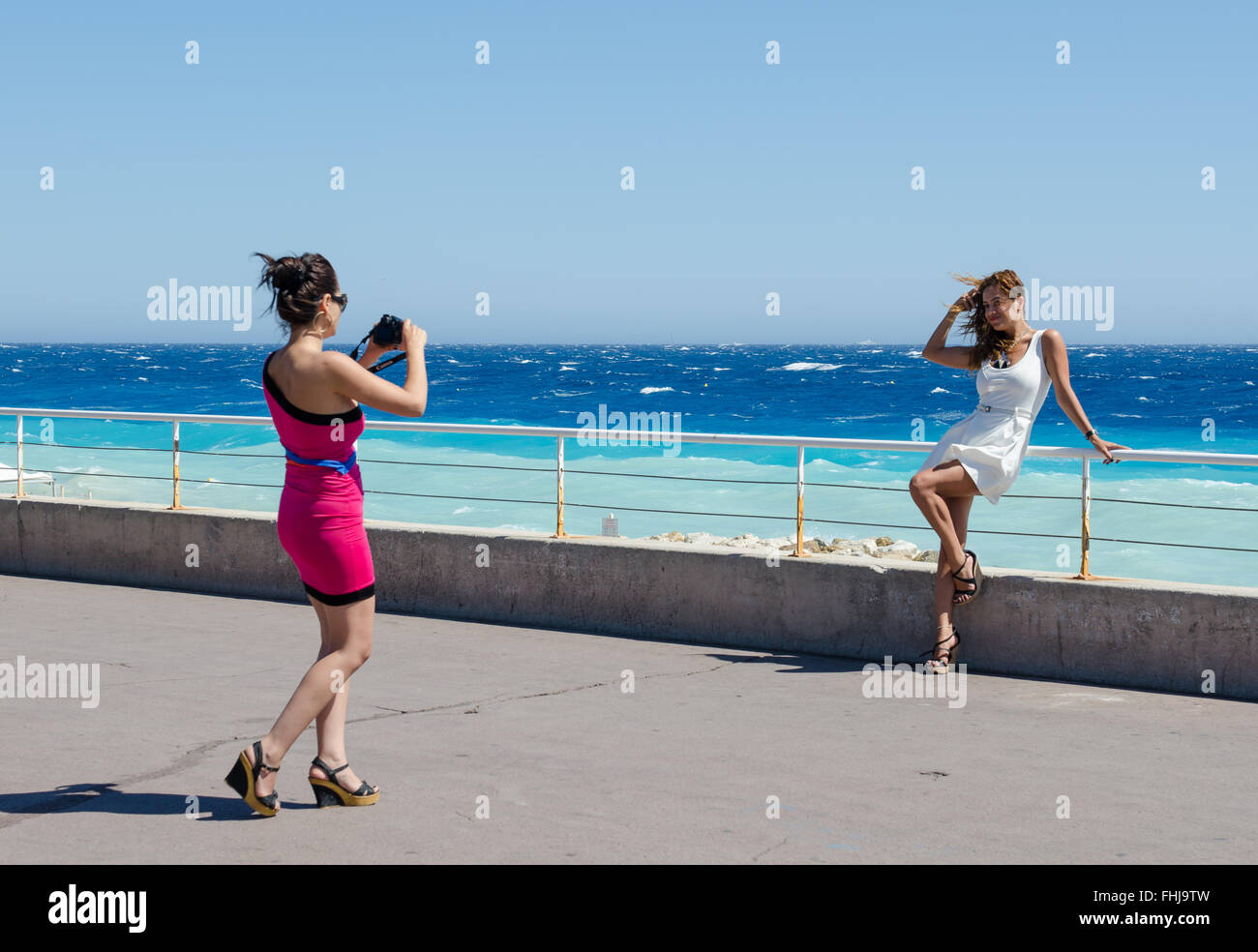 Zwei Freundinnen, die Bilder von einander, wie sie direkt am Meer in Nizza, Frankreich stellen Stockfoto