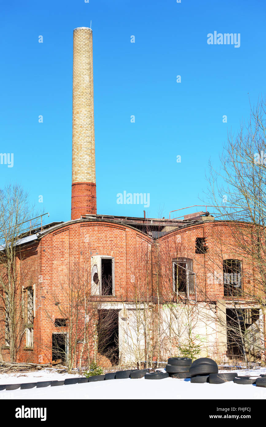 Einem verlassenen Fabrikgebäude mit einem hohen gemauerten Schornstein gegen blauen Himmel. Industriegebiet in Fridafors, Schweden. Stockfoto