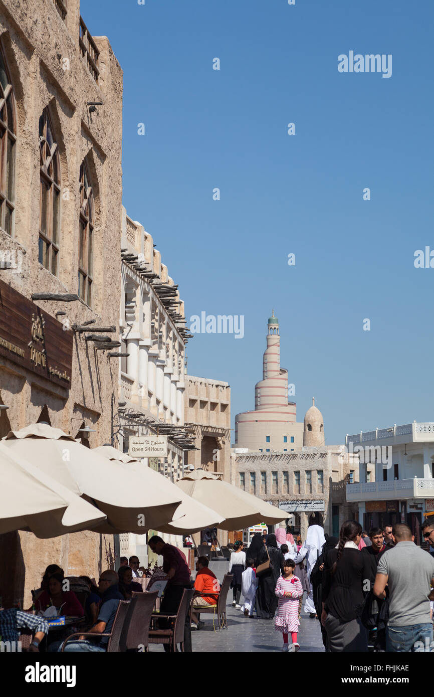 Menschen herumlaufen und Essen im Souq Waqif, Doha, Katar. Fanar in der Ferne. Stockfoto