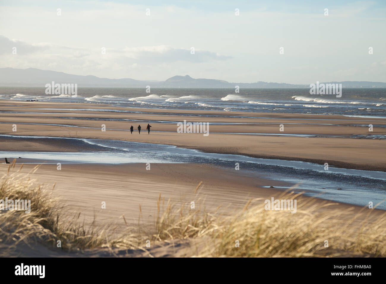 Drei Menschen, die zu Fuß über die große weite hinter Bucht mit Edinburgh in der Ferne. Stockfoto