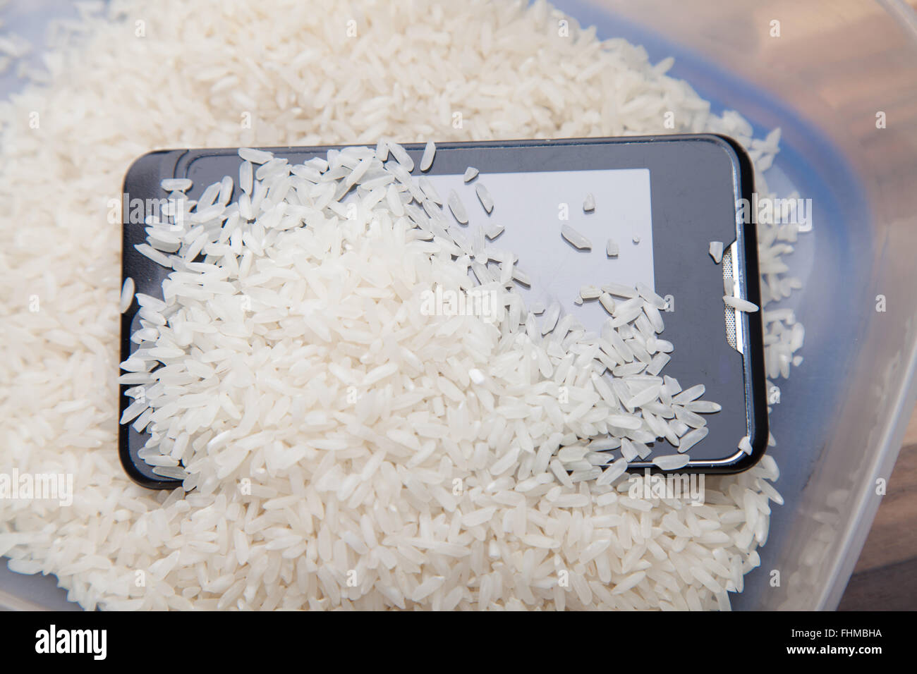 Verwendung von ungekochtem Reis, ziehen Feuchtigkeit von einem Mobiltelefon. Stockfoto
