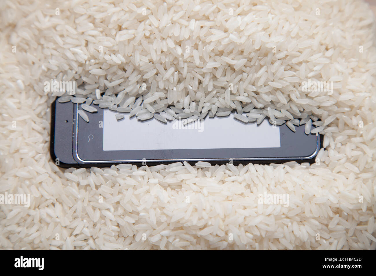 Verwendung von ungekochtem Reis, ziehen Feuchtigkeit von einem Mobiltelefon. Stockfoto
