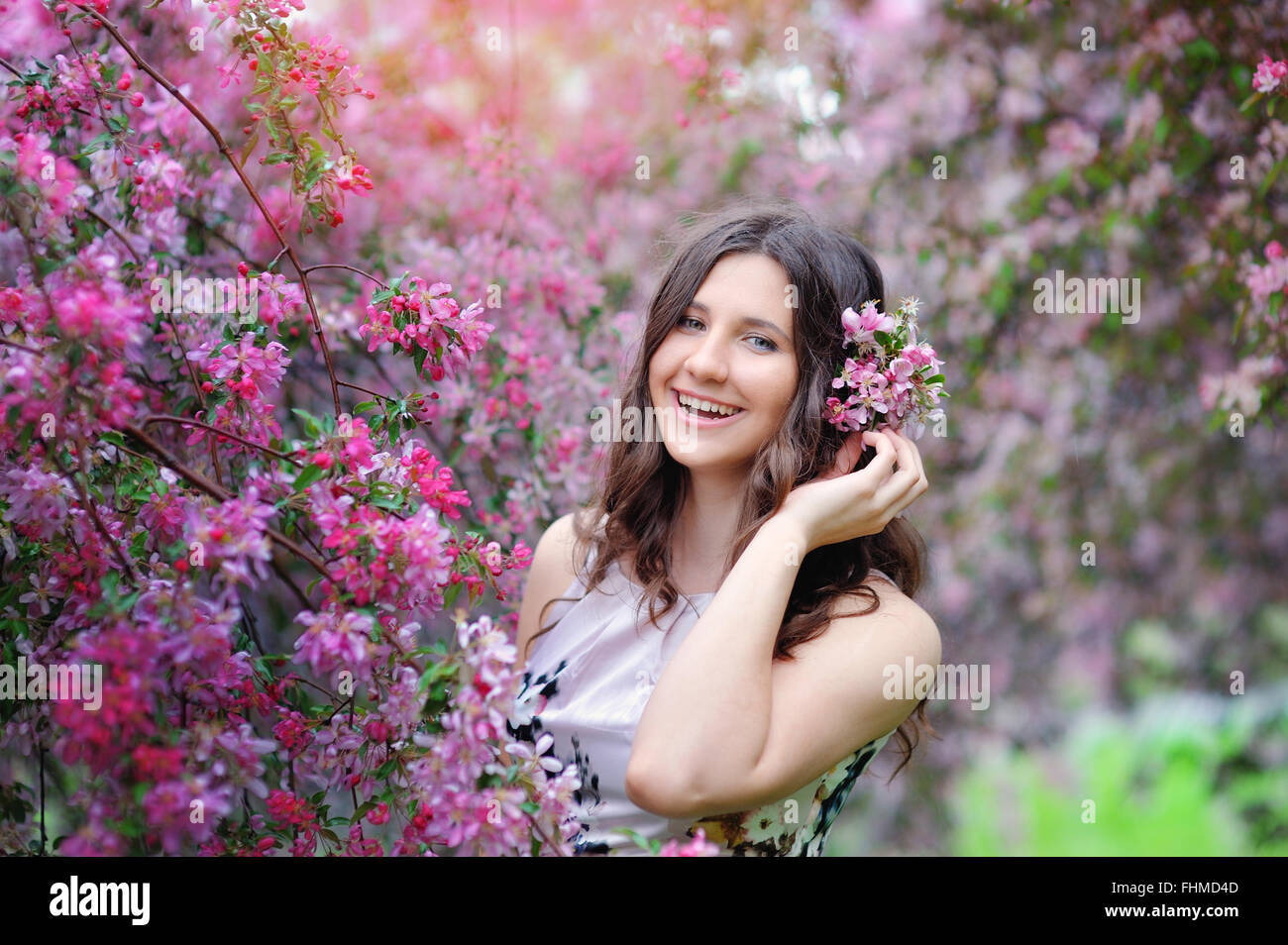 schöne lächelnde Brünette im Blumengarten Stockfoto