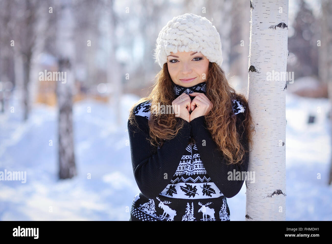 schönes Mädchen in weißen Hut steht in der Nähe der Birke im winter Stockfoto