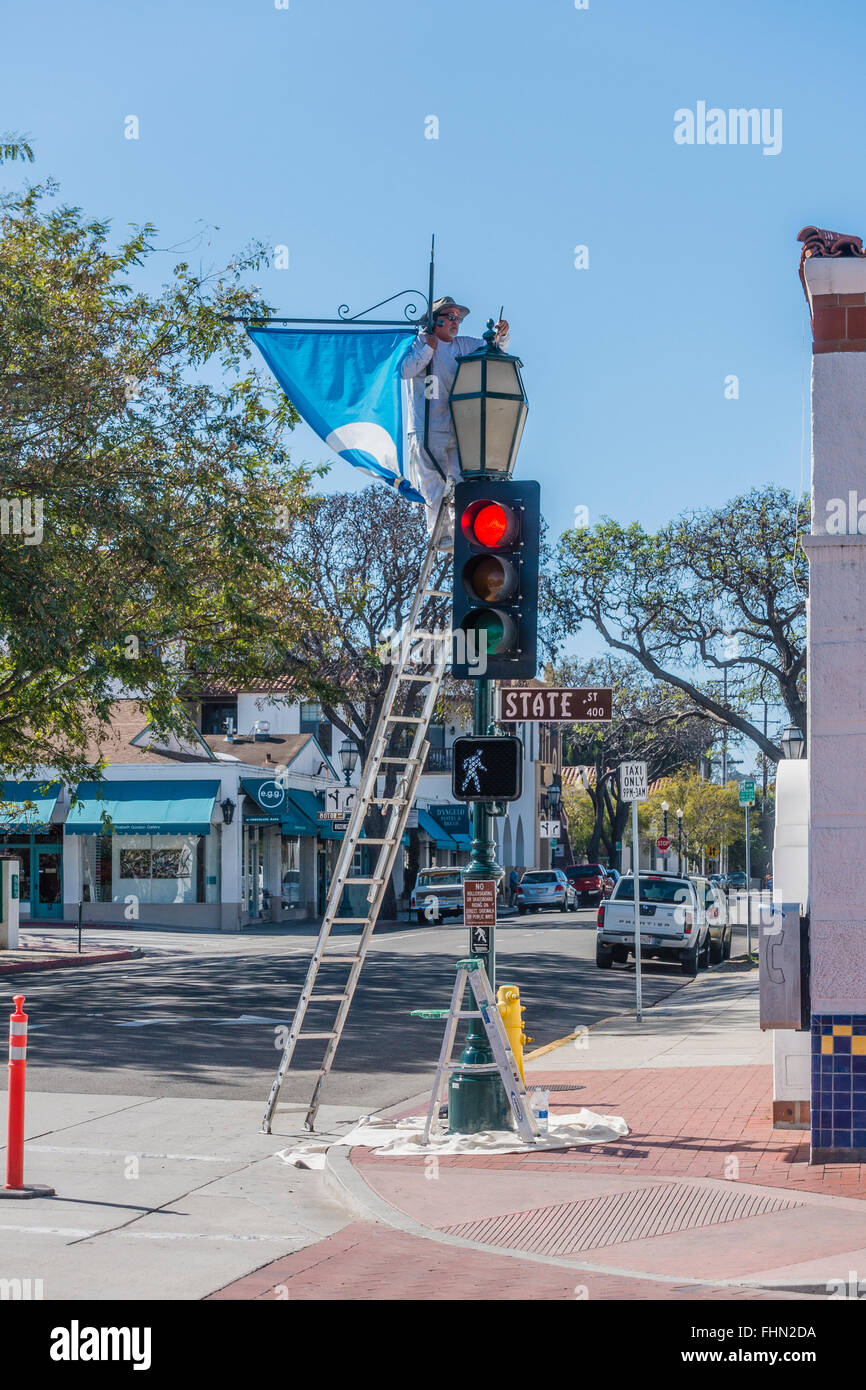 Männlichen spanischen Maler steht auf einer Leiter über seine Tropfen Tuch wie er einen Ampel-Pol malt. Stockfoto