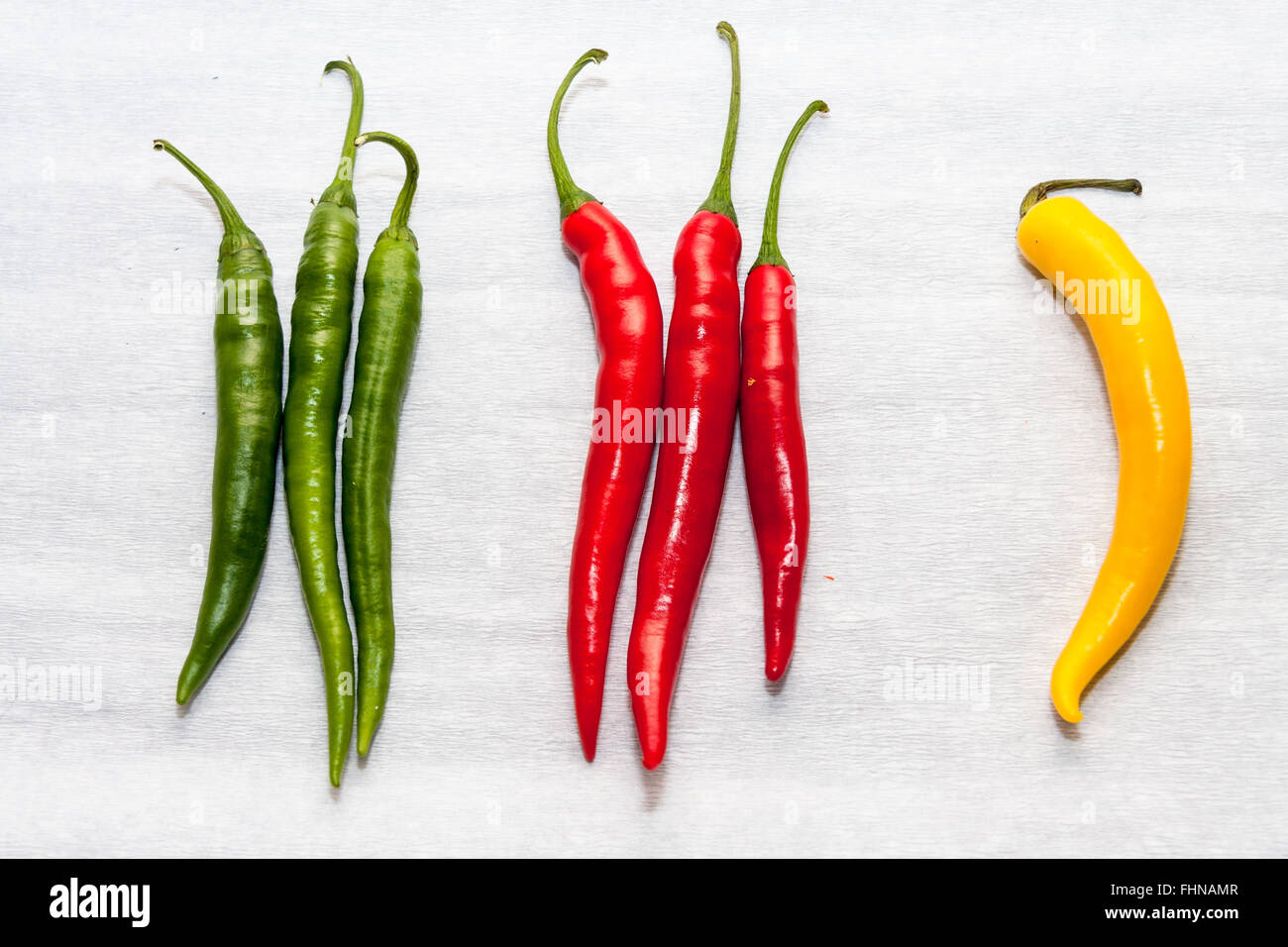 Eine Reihe von Chilis - 3 grün, Pfeffer 3 rote und 1 Gelbe Chili auf weißem Hintergrund Stockfoto