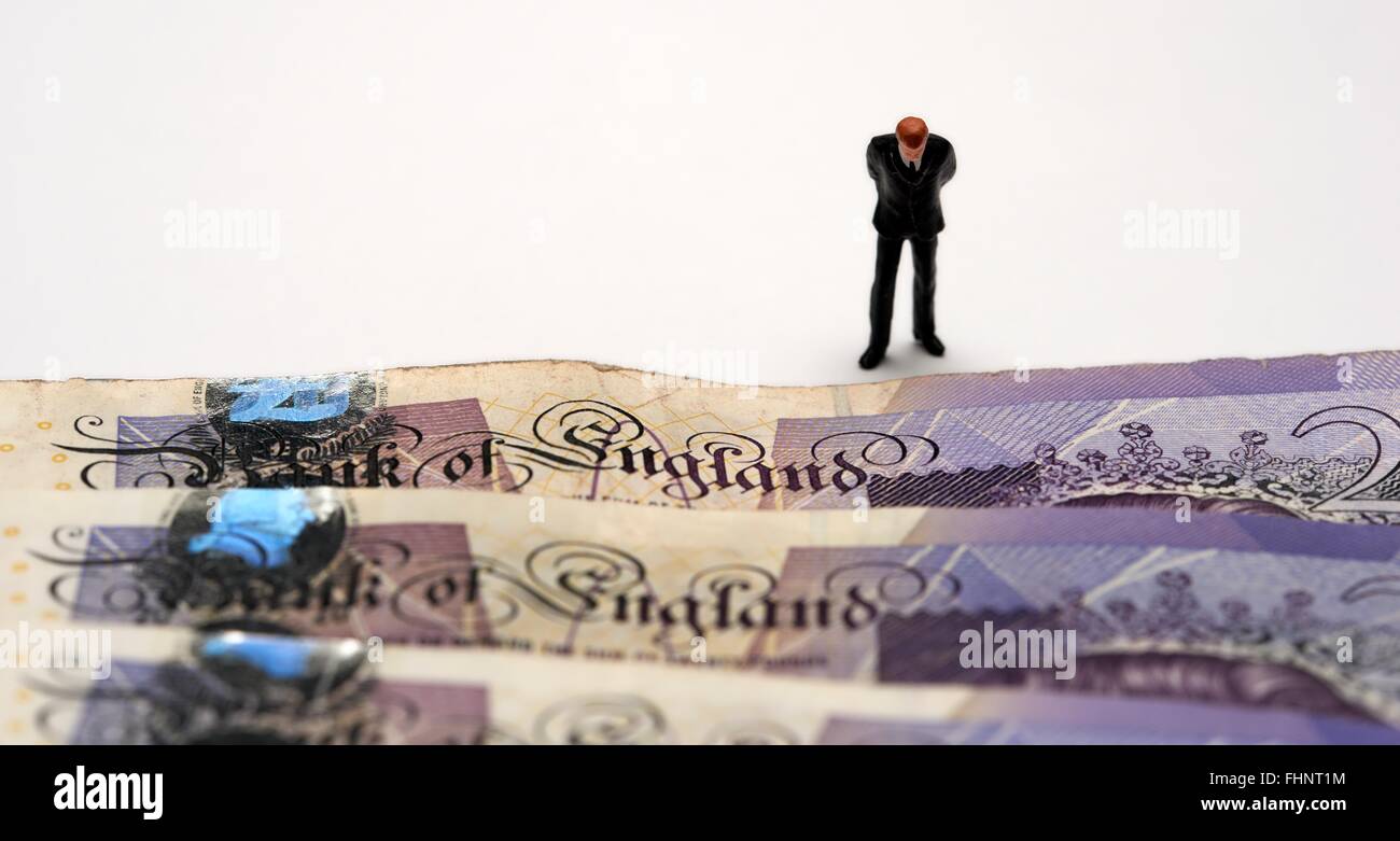 Eine Miniatur Figur Geschäftsmann im Anzug blickte auf die Worte Bank Of England auf einige zwanzig Pfund-Noten Stockfoto