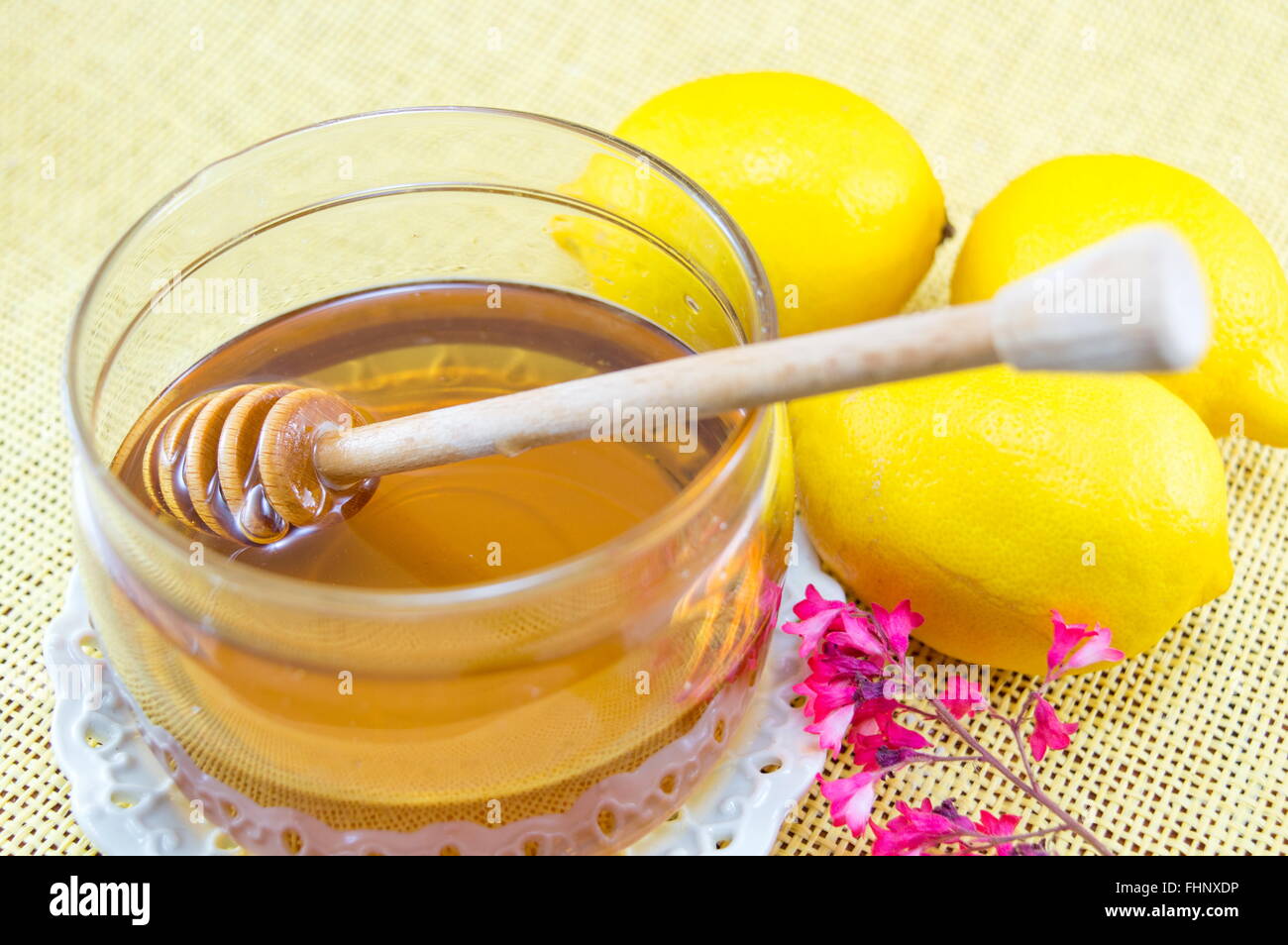 Glas Honig mit einem Löffel aus Holz Wagen und Zitronen Stockfoto