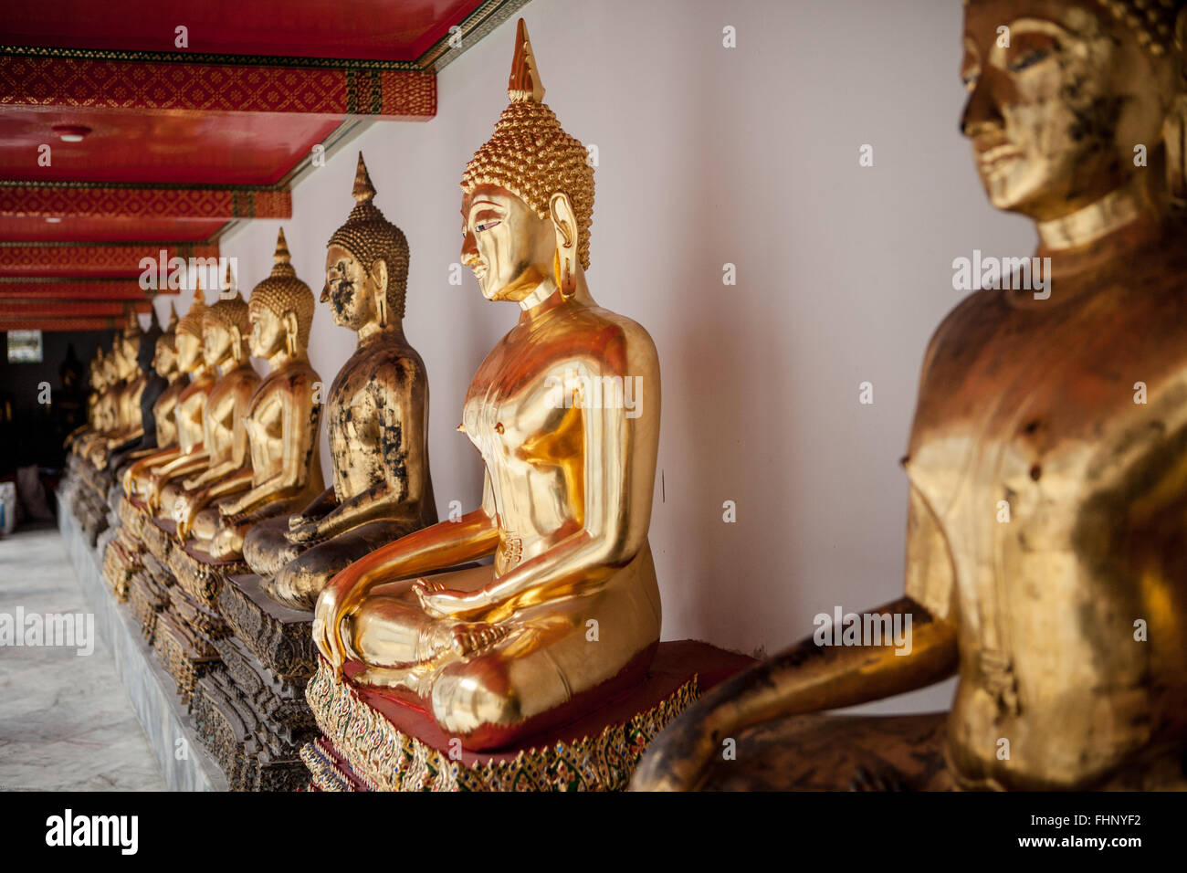 Eine Reihe von sitzen, goldenen Buddha-Statuen im Wat Pho, einem berühmten Tempel in Bangkok, Thailand Stockfoto