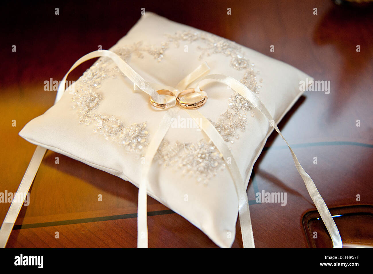 Zwei erstaunliche golden glänzenden Ringe Juwel für Hochzeit Zeremonie Handauflegen weiße schöne Kissen mit Bogen Stockfoto
