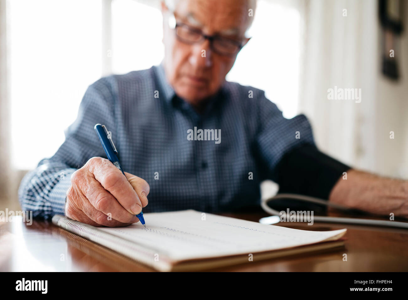 Ältere Mann seinen Blutdruck zu kontrollieren und das Ergebnis aufschreiben Nahaufnahme Stockfoto