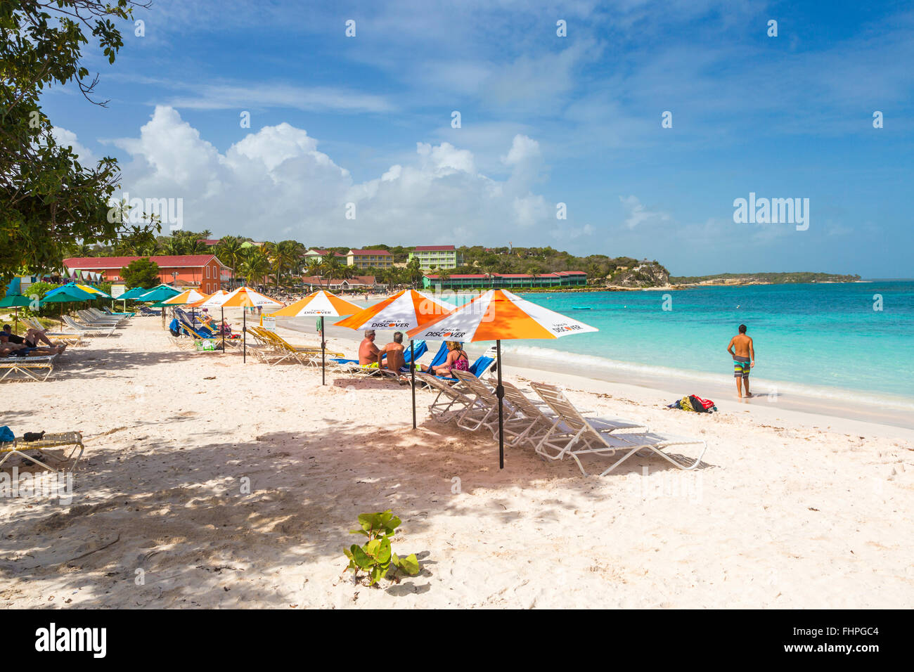 Long Bay, ein beliebter Sandstrand auf der Ostseite der Westindischen Inseln Antigua, Antigua und Barbuda, mit Sonnenliegen und Sonnenschirme Stockfoto