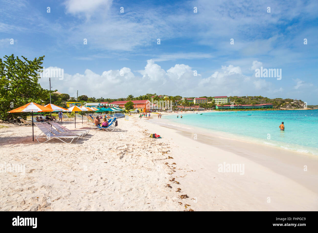 Long Bay, ein beliebter Sandstrand auf der Ostseite der Westindischen Inseln Antigua, Antigua und Barbuda, mit Sonnenliegen und Sonnenschirme Stockfoto