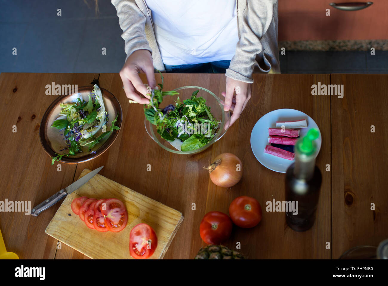 Junge Frau, die einen Salat machen, in der Küche Stockfoto