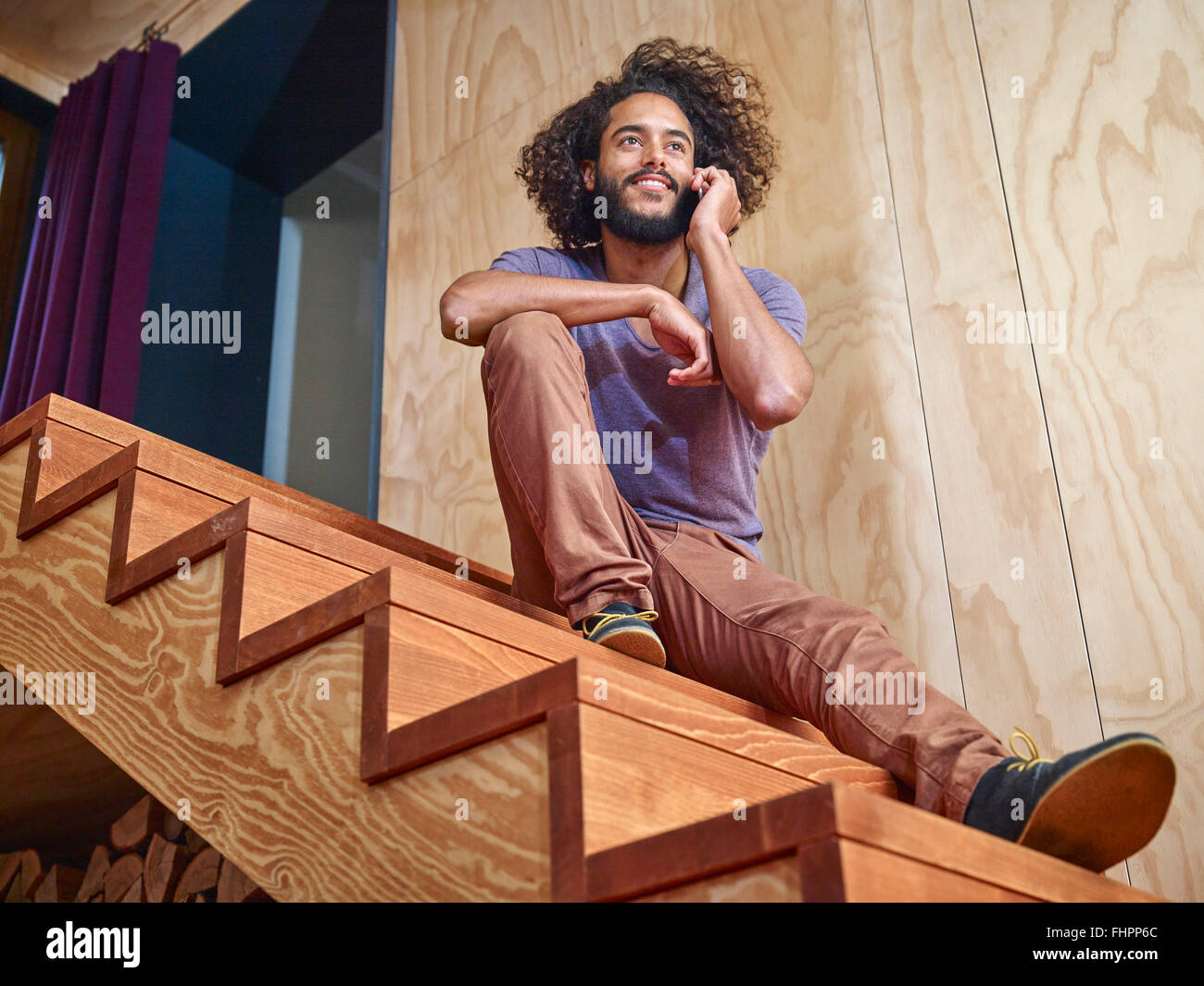 Junger Mann auf Holztreppen reden über Handy Stockfoto