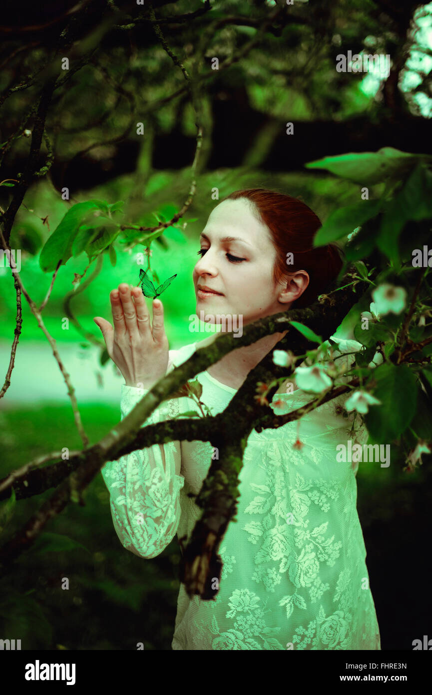 junge Frau im Wald hält einen Schmetterling Stockfoto