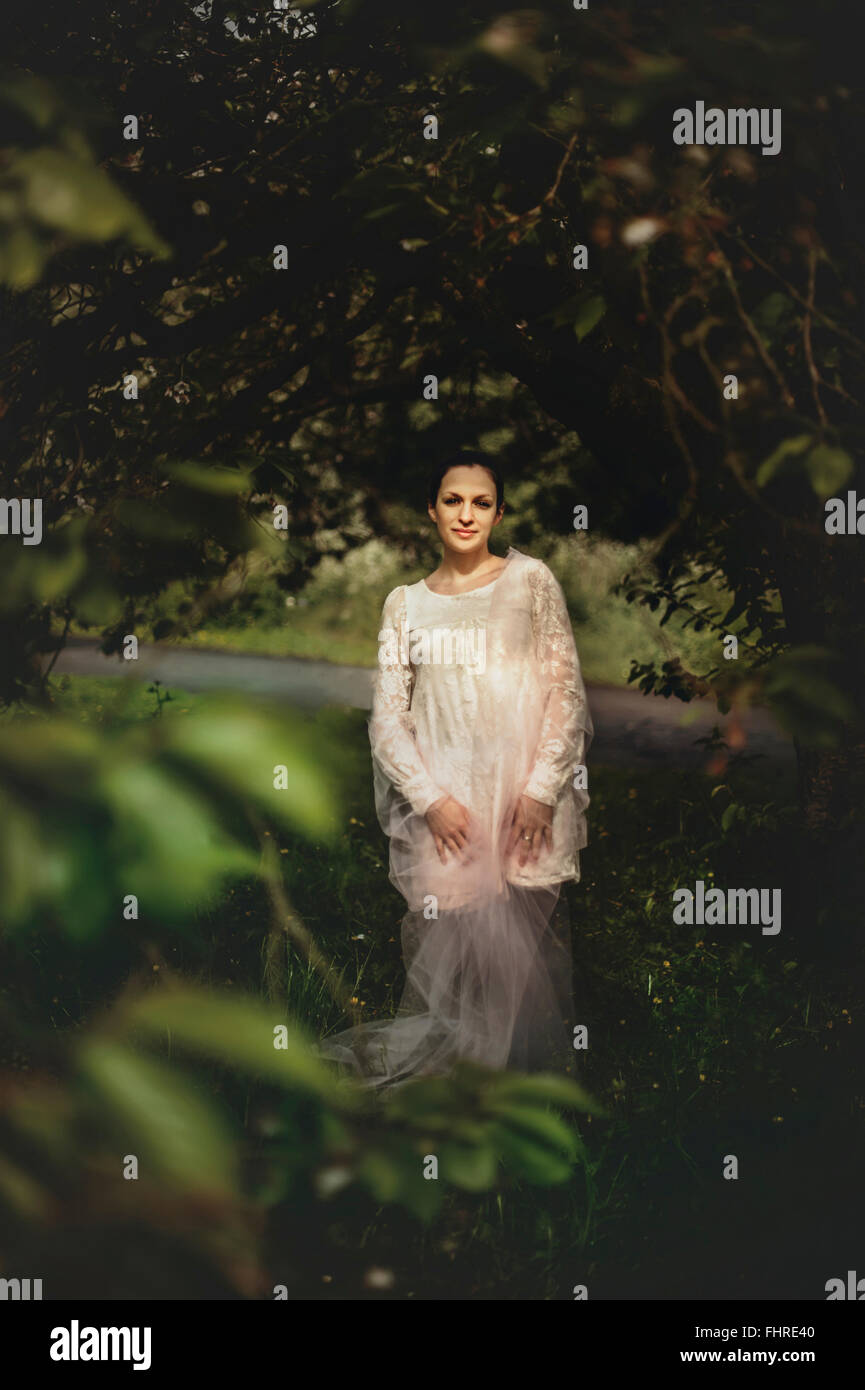 junge Frau trägt weißes Kleid stehend im Wald Stockfoto