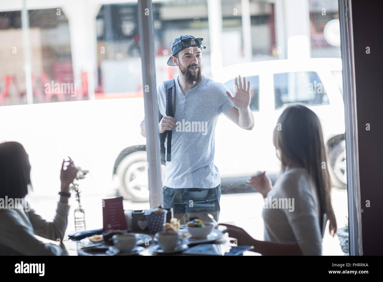 Porträt des jungen Mannes Gruß einen Freund von außerhalb ein Coffee-shop Stockfoto